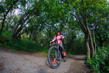 Fototapeta na wymiar Young woman having fun riding a bicycle in the park.