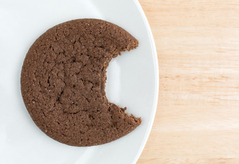 Bitten Dutch cocoa cookie on a white plate