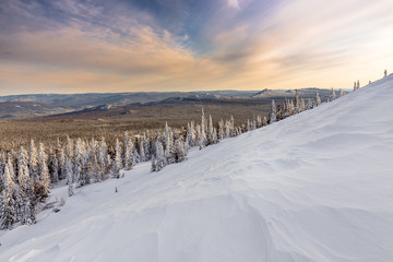 the slope of the mountain with wooded ridge in winter at sunset, Ural, Russia