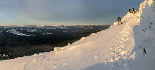 Mountaineer descending from a mountain with  the view of the setting sun over the snowy Ural...