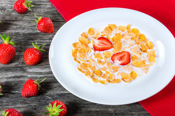 Corn flakes with milk and strawberries, close-up