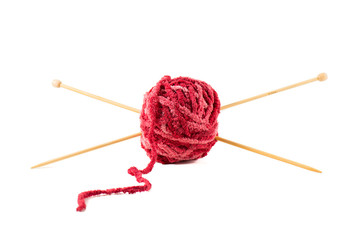 Knitting needles pierce a ball of red wool.