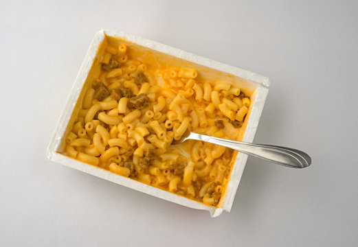 Macaroni and cheese with burger plus fork on an off white tablecloth