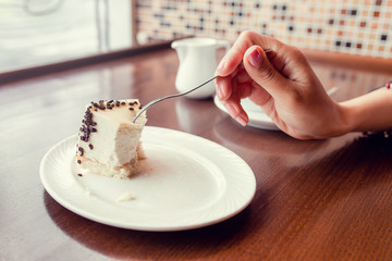 Close up female hand taking a slice of cake with fork