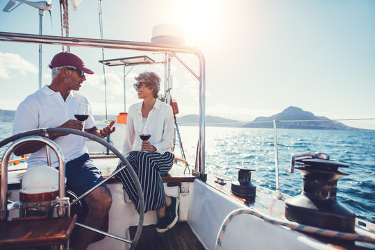 Mature couple talking and enjoying red wine on yacht

