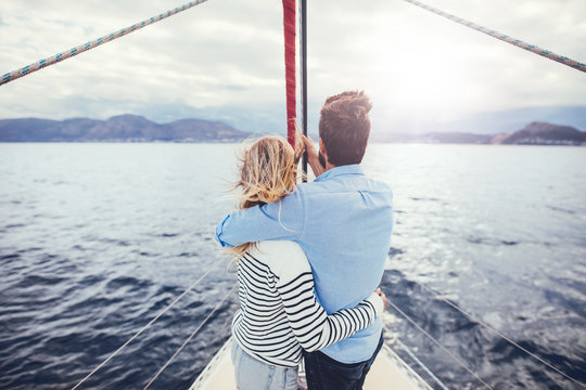 Loving young couple standing in the front of a yacht