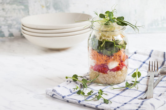 Rainbow salad in a jar, quinoa, tomatoes, mozzarella, spinach, pea sprouts