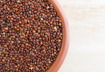 Red quinoa in a small bowl on a wood table top close view