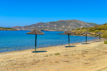 Beautiful sandy beach in Syros, Cyclades, Greece. Straw umbrella