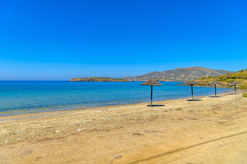 Beautiful sandy beach in Syros, Cyclades, Greece. Straw umbrella
