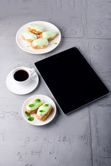Mint eclairs on a plate, coffee and digital tablet with white sc