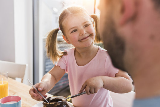 Grinning girl with smeared mouth looking at father