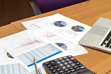 Laptop, calculator and report paper on office wooden desk