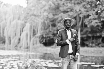 Portrait of stylish rich black man at blue jacket, hat and sungl