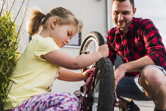 Father and daughter repairing bicycle together