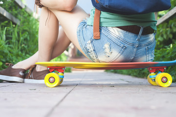 Close-up of skateboarder girl sitting on skateboard outdoor