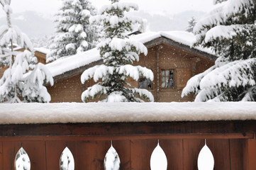 vue d'un balcon sur un  chalet et des sapins sous la neige 