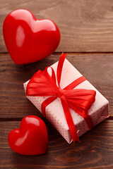 Gift box and decorative hearts on wooden background
