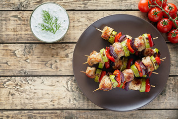 Turkey or chicken meat shish kebab skewers with tzatziki sauce, and tomatoes on rustic wooden table background. Traditional barbecue grill shish food
