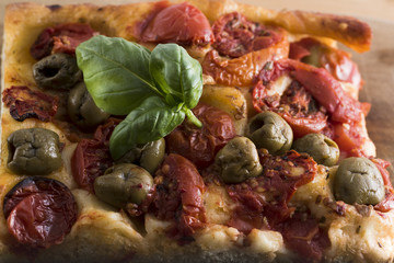 Fresh baked focaccia bread, with olives and tomato pieces.
