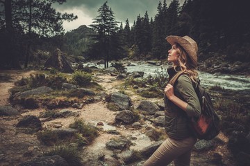 Beautiful woman hiker walking near wild mountain river.