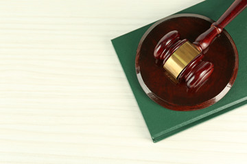 Gavel and book on light wooden background