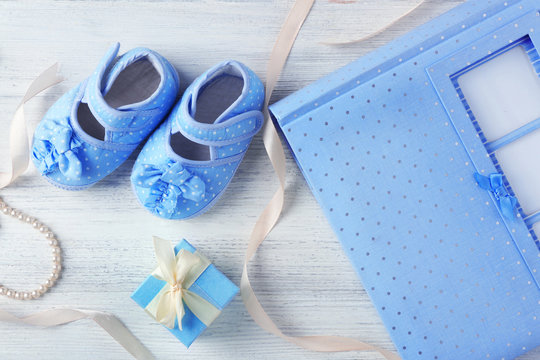 Beautiful composition with baby booties and gift box on wooden background