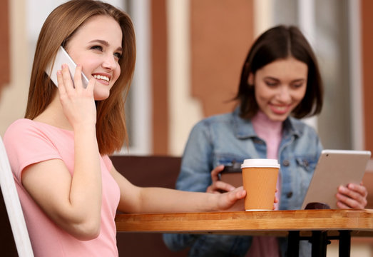 Young happy women drinking coffee and talking in cafe