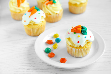 Plate with Easter cupcake on wooden table