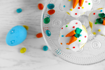 Cake stand with Easter cupcakes and eggs on wooden table