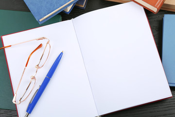 Open book, glasses and pen on table