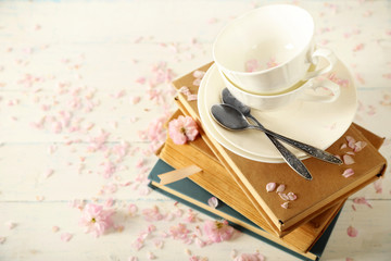 Porcelain cups with books and flowers on table