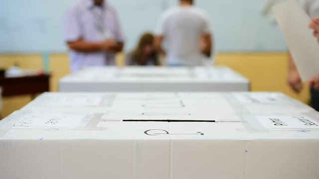 Unrecognizable people casting votes into the ballot box during elections