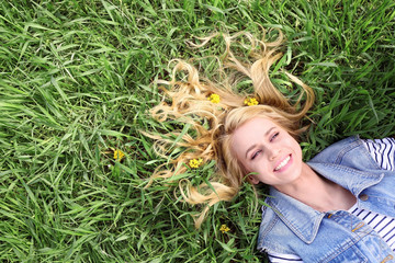 Young beautiful woman with yellow flowers in her hair on green grass