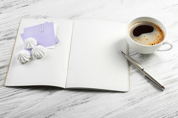Cup of fresh coffee and notebook on wooden background