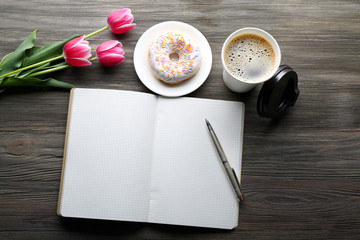 Cup of fresh coffee and notebook on wooden background