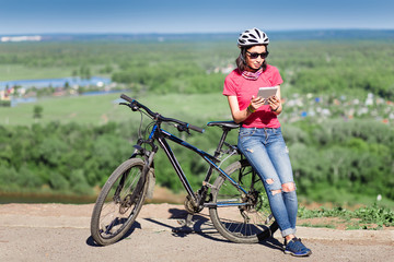 Sport bright girl with helmet sitting with digital tablet pc in the sunny park