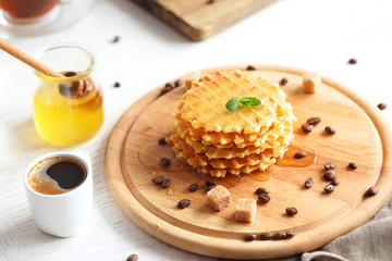 Tasty waffles with coffee on cutting board