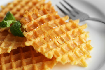 Tasty waffles with honey and mint on plate