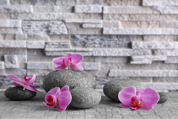 Beautiful composition of pebbles and orchid on grey background