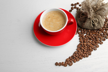 Cup of coffee with beans on light background