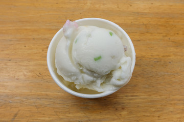 Homemade coconut icecream in paper cup on the wooden table.