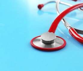 Red stethoscope on blue surface, closeup