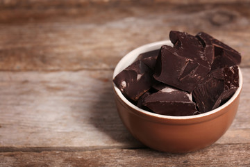 Chocolate bar pieces in a bowl on wooden background