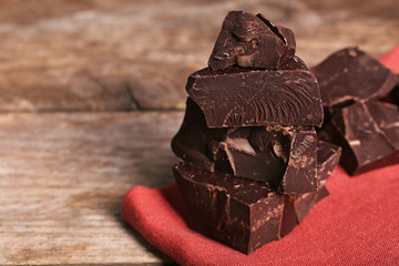 Chocolate bar pieces on red napkin on wooden background