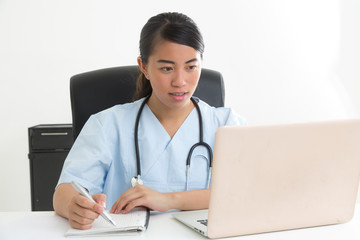 Fototapeta na wymiar Young asian medical assistant sitting at desk and taking notes