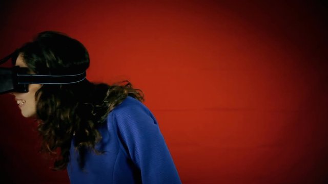 A pretty woman wearing a virtual reality headset and wired gloves, having a wow experience inside a VR world.