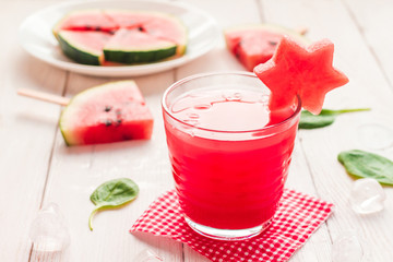 watermelon juice and watermelons slices on wooden white backgrou