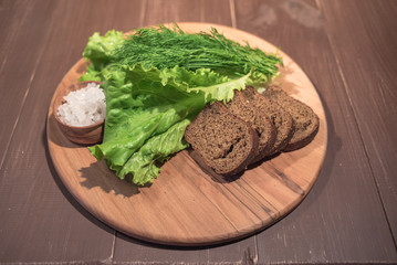 Lettuce and dill on wood plate with rye bread and sea salt

