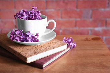 Purple lilac flowers in a cup on red brick wall background